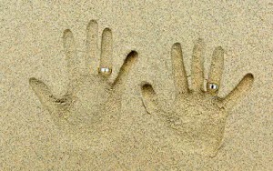 在沙灘上壓手印，並把婚戒戴在手印上